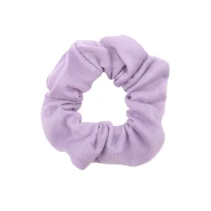 Dettaglio in primo piano di un morbido elastico per capelli in tessuto viola chiaro.