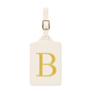 Etiquette de bagage en cuir PU beige avec lettre B brodée dorée et boucle métallique voyage.