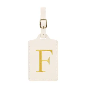 Élégante étiquette de bagage beige avec lettre F brodée en or et boucle métallique.