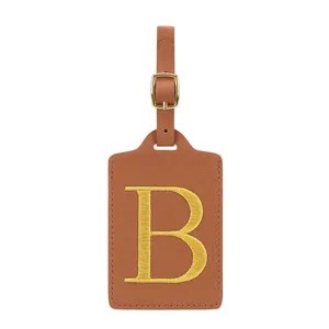 Vue détaillée d'une étiquette de bagage en cuir PU marron avec lettre B brodée dorée et boucle.