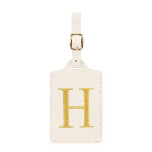 Vue détaillée d'une étiquette de bagage en cuir blanc crème avec broderie dorée lettre H.
