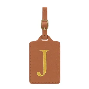 Étiquette de bagage élégante en cuir PU marron avec lettre brodée dorée et boucle métallique.