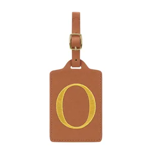 Gros plan détaillé d'étiquette de bagage en cuir PU marron avec boucle dorée et lettre O brodée.