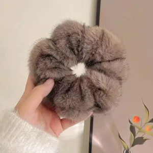 Dettaglio scrunchie in pelliccia sintetica visone marrone, elastico morbido per capelli.