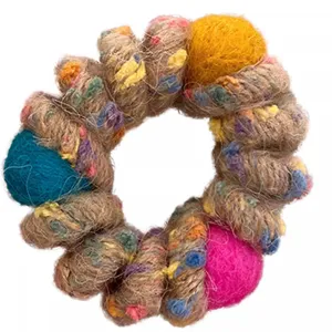 Detailed close-up of the colorful twine wrapped hair tie with cute felt ball ornaments.
