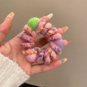 Close-up detail of colorful woolen yarn wrapped telephone wire hair scrunchie with cute balls.