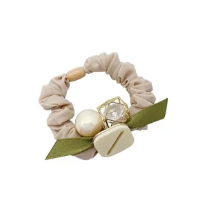 Primo piano dettagliato di un elegante elastico per capelli con perla e nastro verde.