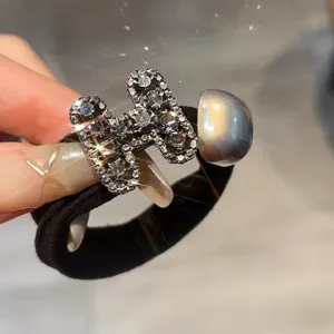 Close-up of rhinestone H-shaped hair tie with black elastic band and chic pearl detail