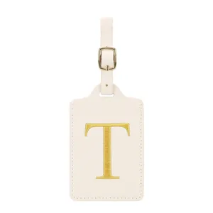 Gros plan détaillé d'étiquette de bagage en cuir beige avec lettre T brodée en or et boucle.