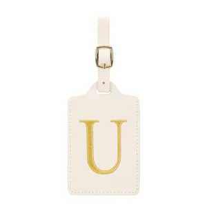 Vue detaillee de l'etiquette de bagage en cuir PU beige avec elegante lettre U brodee d'or.