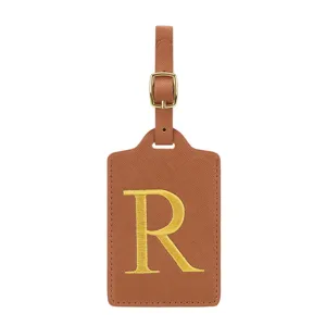 Vue détaillée de l'étiquette de bagage en cuir PU marron avec lettre R brodée dorée et une boucle.