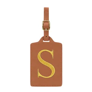 Étiquette de bagage en cuir PU marron avec lettre S brodée dorée et détail de boucle.