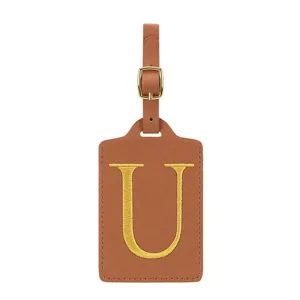 Détail d'étiquette de bagage en cuir PU marron, boucle dorée et lettre U brodée.