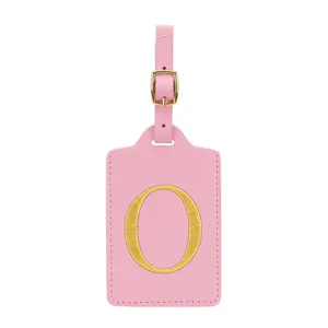 Etichetta per valigia in ecopelle rosa con lettera O ricamata dorata, accessorio da viaggio.