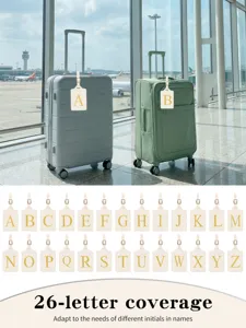 Etiquettes de bagage personnalisees en cuir beige avec lettres brodees dorees pour voyage.