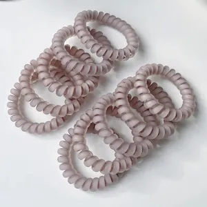 Detail shot of matte telephone cord hair ties, featuring soft dusty pink color and high elasticity.