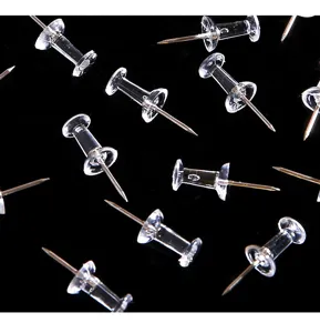 Transparent plastic pushpins detail shot showing clear thumbtacks on dark background.