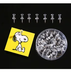 Detail view of transparent pushpins in a round storage box and pinned on a note.