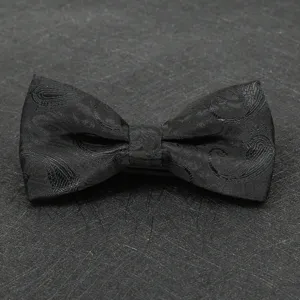 Black paisley bow tie detail shot, elegant fabric texture for formal wedding suit wear.