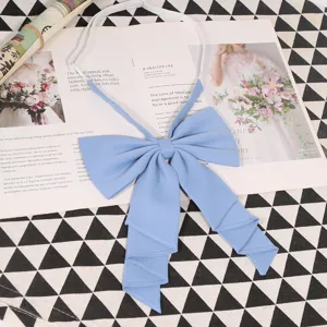 Close up view of light blue solid color big bow tie for JK uniform, featuring fine pleated fabric.