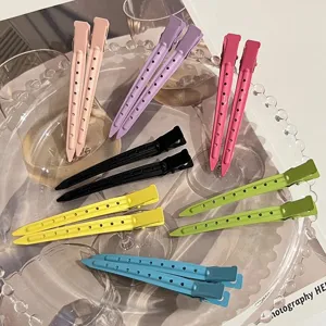 Detailed close-up of colorful duckbill hair clips with ventilation holes, set on a glass tray.