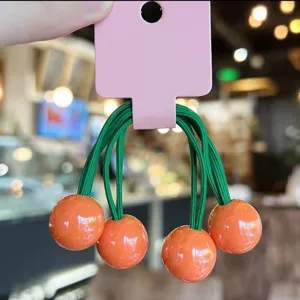Cute candy-colored spherical hair ties detail view, green elastic bands with orange beads.