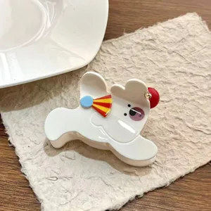 Primer plano de una bonita pinza de pelo acrílica de oso de circo con detalle de gorro festivo.