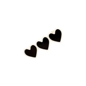 Close-up detail of black heart hair clip with white trim, cute side styling accessory.