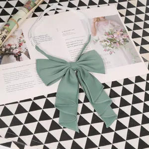 Close-up detail of the elegant green JK uniform bow tie with layered pleats and elastic strap.