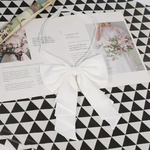 Solid white bow tie for JK uniform, elegant pleated ribbon necktie close-up detail view.