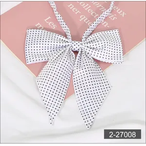 Close-up detail of a white JK uniform bow tie featuring classic black polka dot pattern.