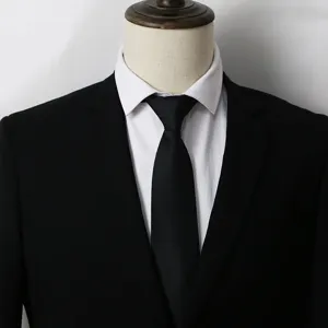 Gros plan d'une cravate noire élégante associée à une chemise blanche et un costume.