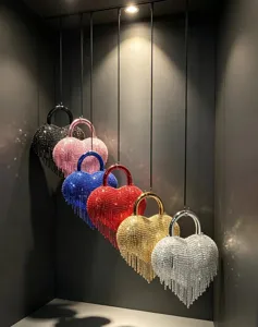 Détail du sac de soirée cœur en strass scintillant avec franges élégantes et poignée métallique.