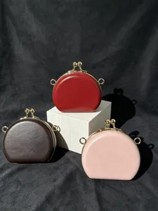Detailopname van kleine ronde PU handtassen met metalen beugelsluiting in rood, bruin en roze.
