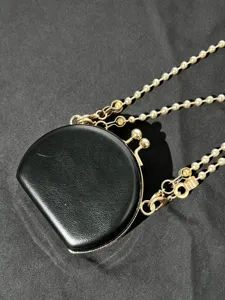 Kleine zwarte PU lederen lipsticktas met gouden kussensluiting en parelketting riem.