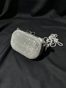 Nahaufnahme einer glitzernden silbernen Strass-Clutch mit elegantem Kettenriemen und Verschluss.