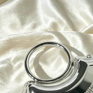 Nahaufnahme des eleganten silbernen Metallringgriffs und funkelnden Kristallquasten-Abendtasche.