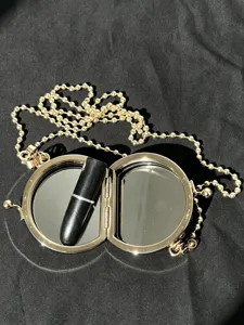 Gedetailleerde close-up van een ronde mini cosmetische doos tas van metaal met ketting.