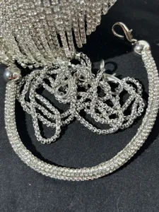 Photo de détail d'un sac de soirée à franges de strass avec cristaux et chaîne argentée.
