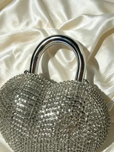 Dettaglio borsa da sera a cuore in strass scintillanti con manico in metallo argentato lucido.