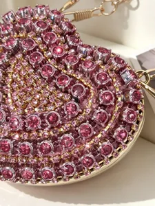 Detaillierte Nahaufnahme der glitzernden rosa Strass Herz Abendtasche mit goldener Kette.