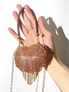 Detailaufnahme einer glitzernden Strass-Herz-Abendtasche mit zarten Quasten und Kettenriemen.