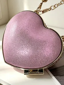 Rosa herzförmige Abendtasche Detail, glitzernde Textur mit goldener Kante und Kette.