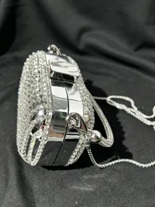 Detailaufnahme einer silbernen Strass-Abendtasche mit Metallrahmen und edler Kette.