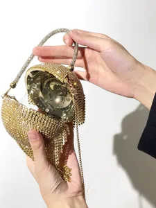 Détail de pochette de soirée boule en strass scintillants avec franges et design métallique.