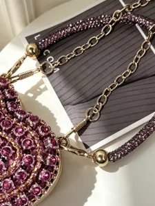 Nahaufnahme der luxuriösen Herz-Strass-Mini-Abendtasche mit funkelnden Kristallen und Goldkette.