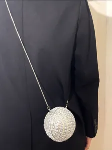 Detail view of a sparkling rhinestone spherical evening crossbody bag with a delicate silver chain.