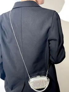 Detailaufnahme einer glitzernden Strass-Acryl-Clutch, die quer über dem Körper getragen wird.