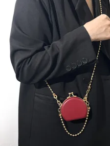 Close-up van een mini rode PU-lederen portemonnee met goudkleurige ketting en kussenslot.