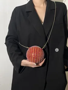 Detailed view of the sparkling rhinestone spherical evening bag with a delicate gold chain strap.